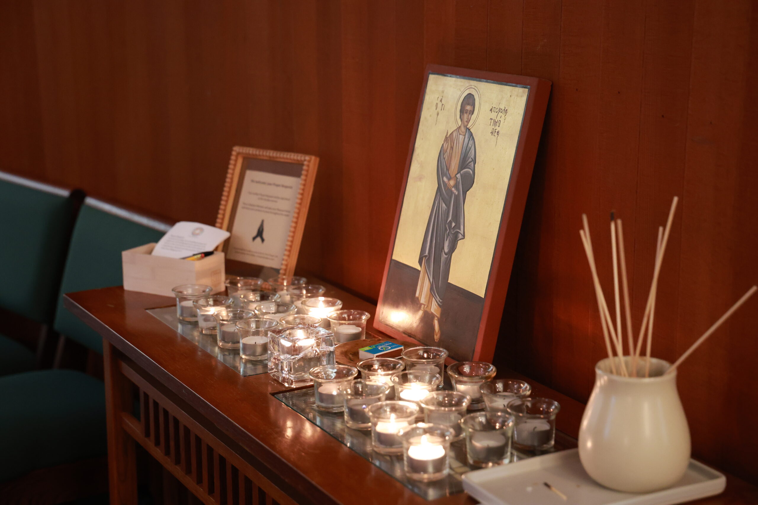 Lit candles in front of an icon of St. Timothy