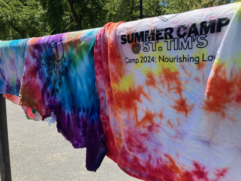 A row of tie-dyed summer camp t-shirts