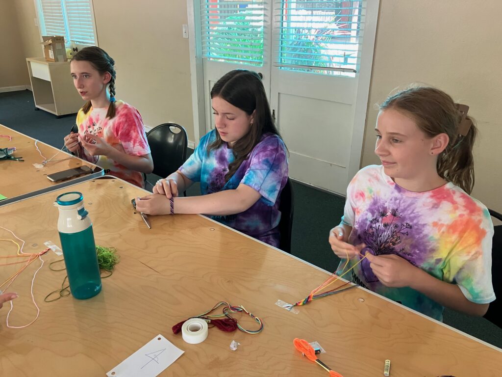 Kids in tie-dye making friendship bracelets