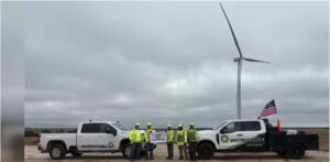 A large wind turbine above several trucks