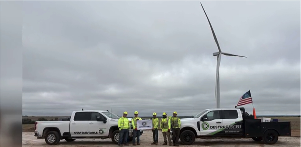 A large wind turbine above several trucks