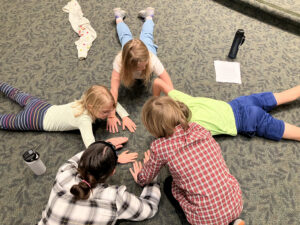 Youth laying on the floor in a circle playing a hand game