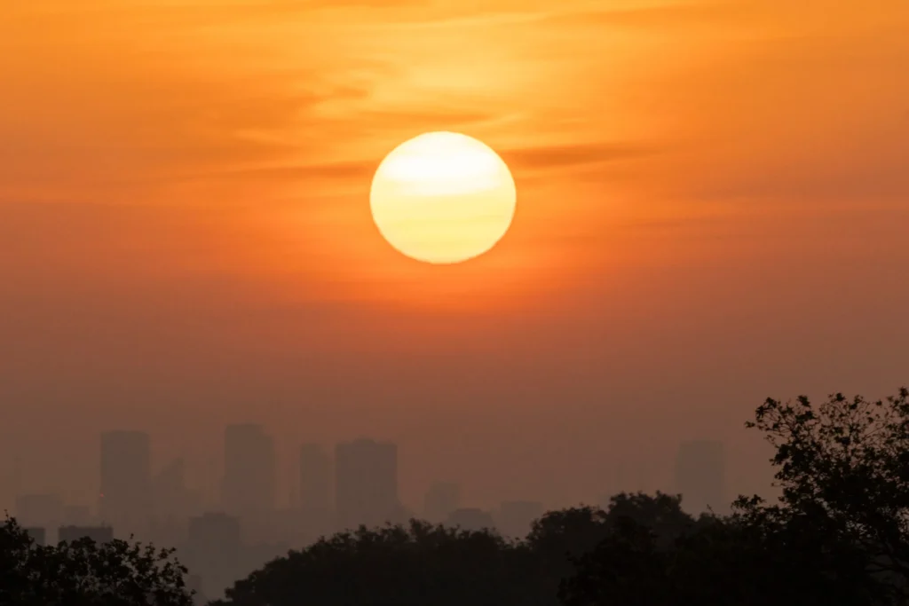 An orange sun rising over a city