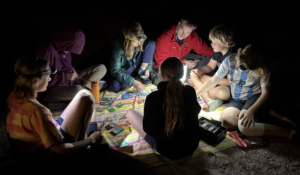 A group of youth playing a game in the dark on a camping trip