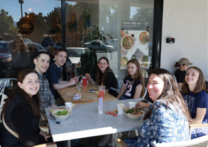 Shows people eating lunch and smiling
