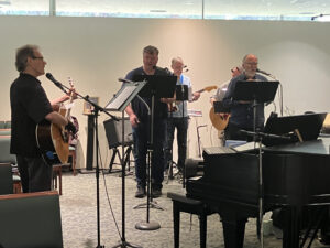 People singing and our music director Peter playing guitar