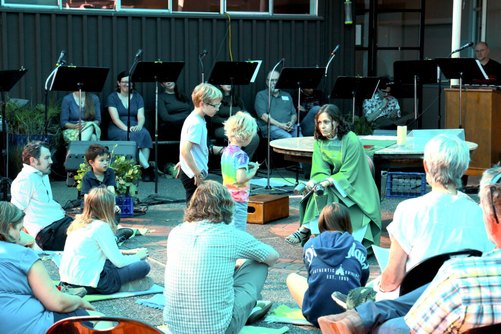 A priest shows kids different kids of dirt during a sermon outside