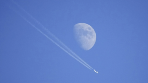 Flight paths and a moon in a blue sky