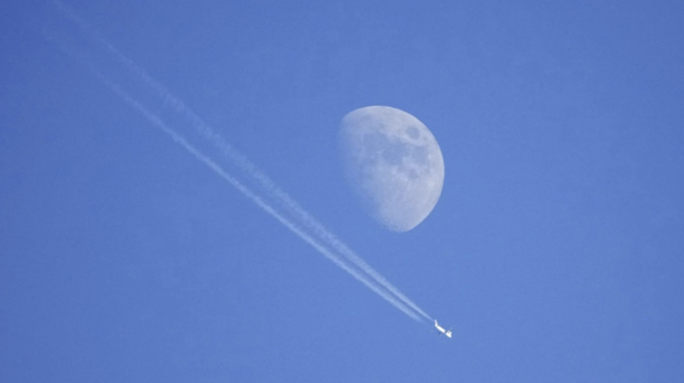 Flight paths and a moon in a blue sky