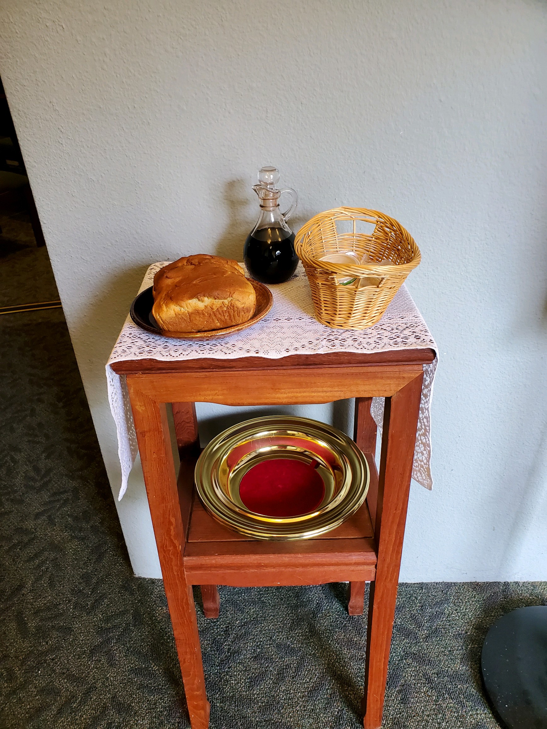 A table set up with bread, wine, and a basket to be brought forward for communion.