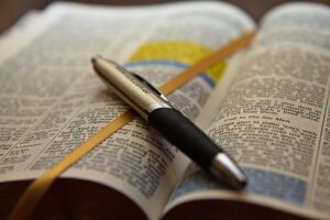 An open bible with a pen lying on top