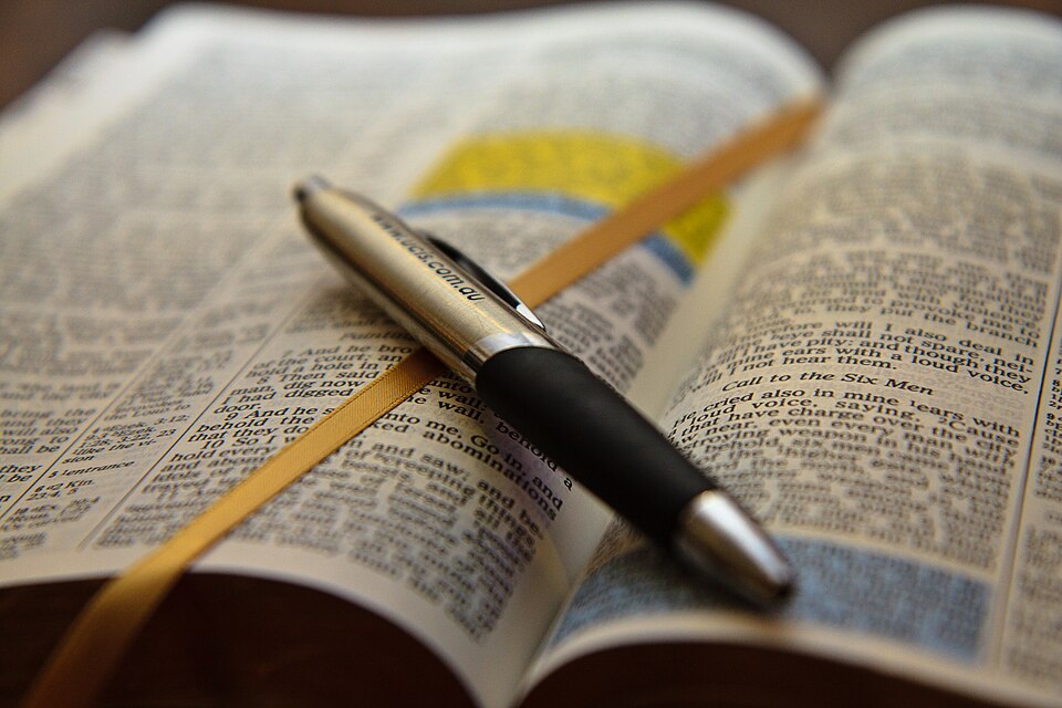 An open bible with a pen lying on top