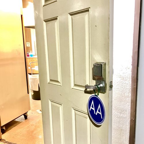 A door stands open with the Alcoholics Anonymous (AA) welcome sign