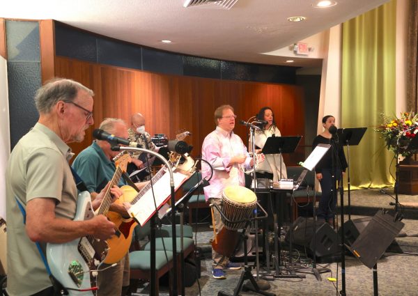 Band members playing guitar, drums, and tambourine at St. Timothy's church service.
