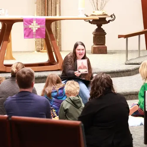A woman holding up an icon to show young people at the 9am children's service