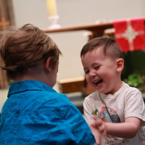 two children offering one another peace with huge grins