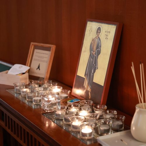 Lit candles in front of an icon of St. Timothy