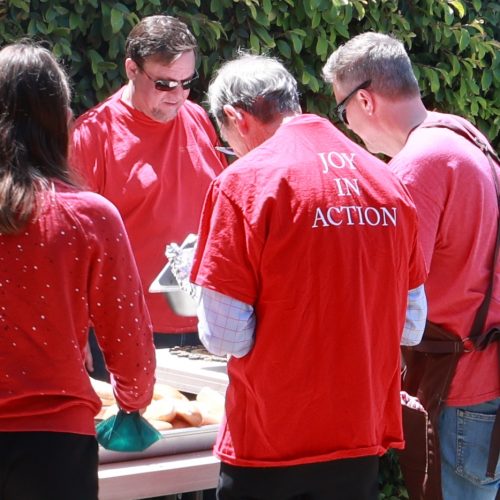 A red shirt reads "Joy in Action."