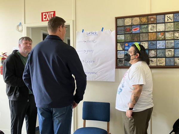 Adults gathered around a page about how we Gather as church