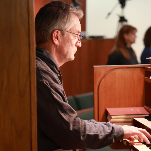 A man playing the organ in a church service.